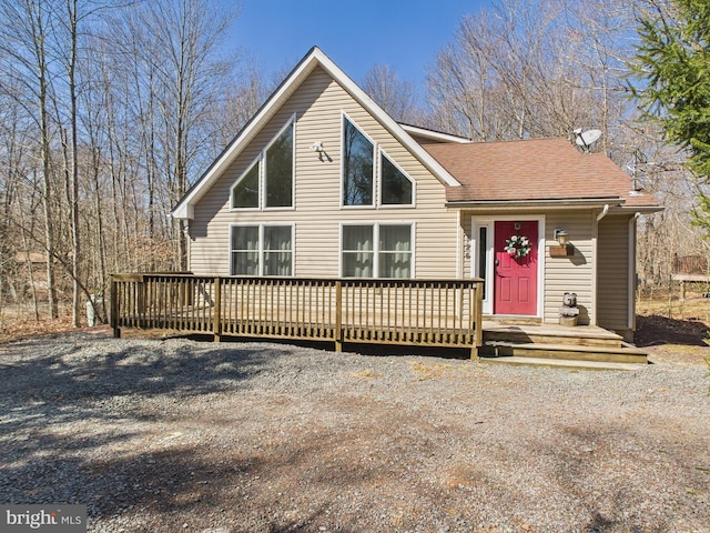 rustic home featuring a deck and roof with shingles