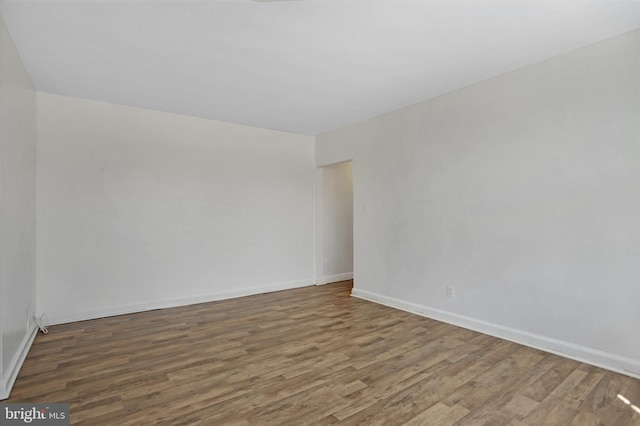 spare room with baseboards and wood finished floors