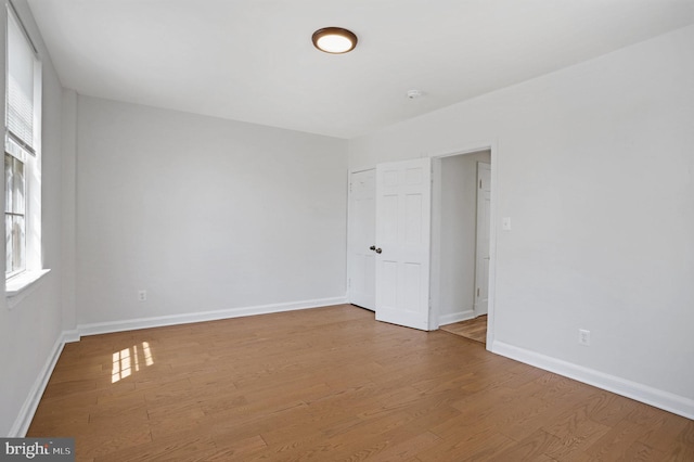 spare room featuring a healthy amount of sunlight, baseboards, and wood finished floors