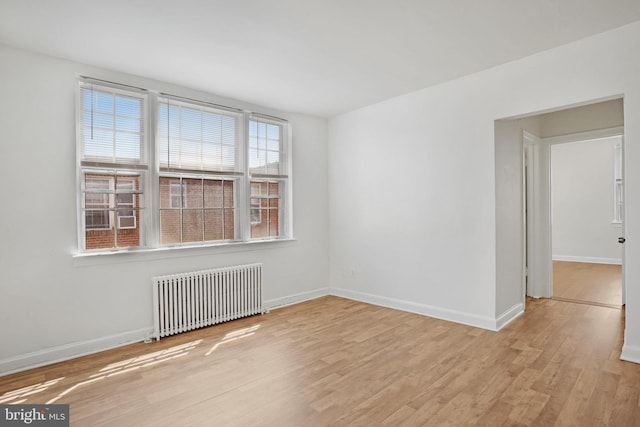 empty room featuring radiator heating unit, baseboards, and wood finished floors