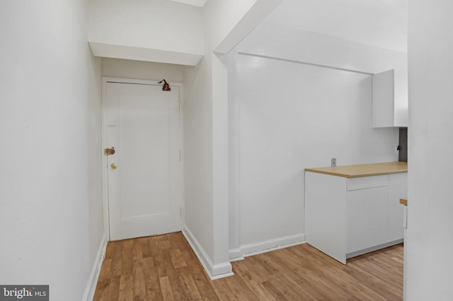 corridor with baseboards and light wood-type flooring
