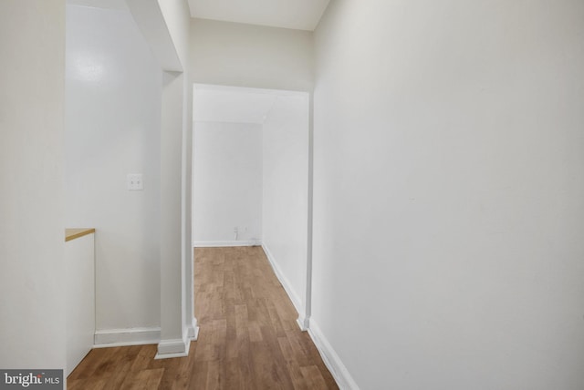 corridor with baseboards and wood finished floors