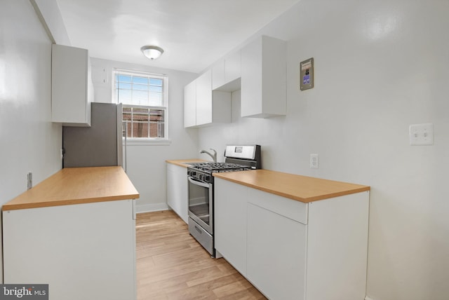 kitchen with light countertops, stainless steel appliances, light wood finished floors, and white cabinetry