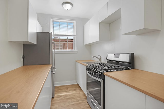 kitchen with light countertops, white cabinets, a sink, light wood-style flooring, and stainless steel appliances