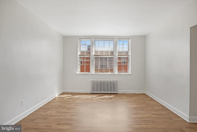 empty room featuring radiator, baseboards, and wood finished floors