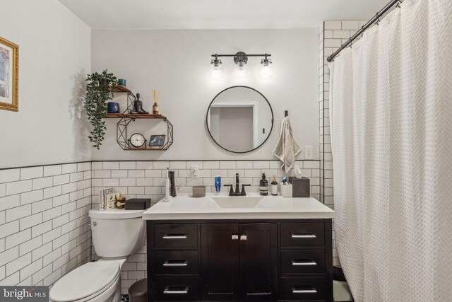 full bathroom with a wainscoted wall, toilet, tile walls, and vanity