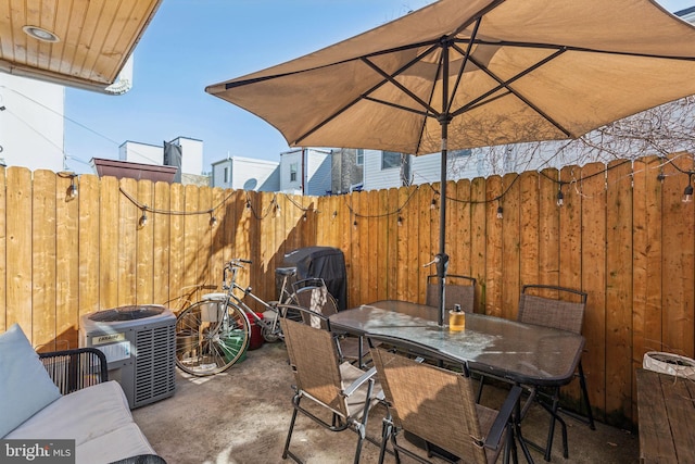 view of patio featuring central AC unit, outdoor dining area, and fence