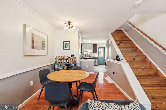 dining room featuring stairs, light wood-style floors, baseboards, and ornamental molding