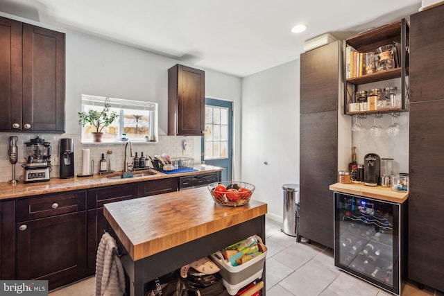 kitchen with a sink, wooden counters, backsplash, and wine cooler