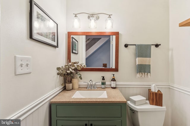 bathroom featuring a wainscoted wall, toilet, and vanity