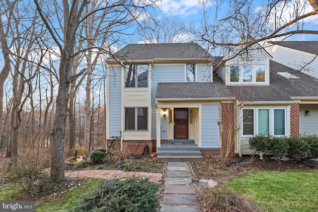 view of front of home featuring brick siding and a shingled roof