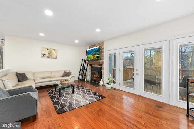 living room featuring recessed lighting, a large fireplace, and wood-type flooring