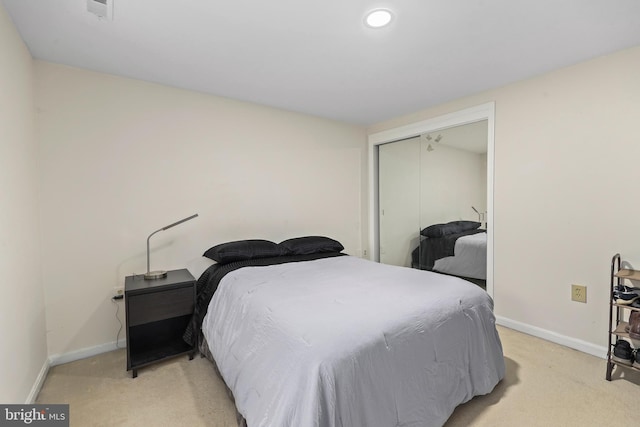 bedroom with a closet, light colored carpet, and baseboards