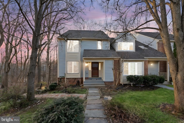 view of front facade featuring a shingled roof, brick siding, and a chimney