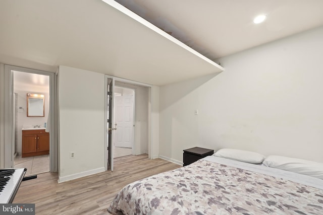 bedroom featuring light wood-style flooring, baseboards, and connected bathroom