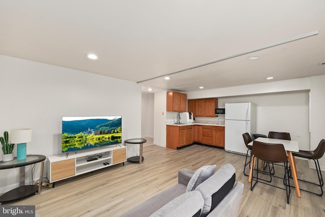 living area with recessed lighting, light wood-type flooring, and baseboards