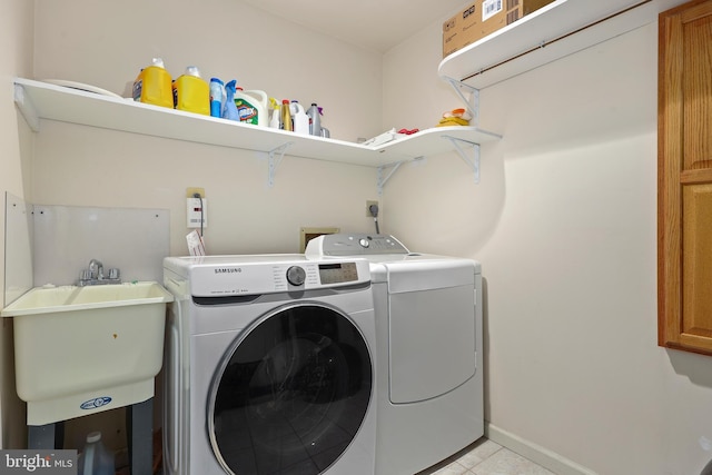 laundry room featuring a sink, cabinet space, separate washer and dryer, light tile patterned floors, and baseboards