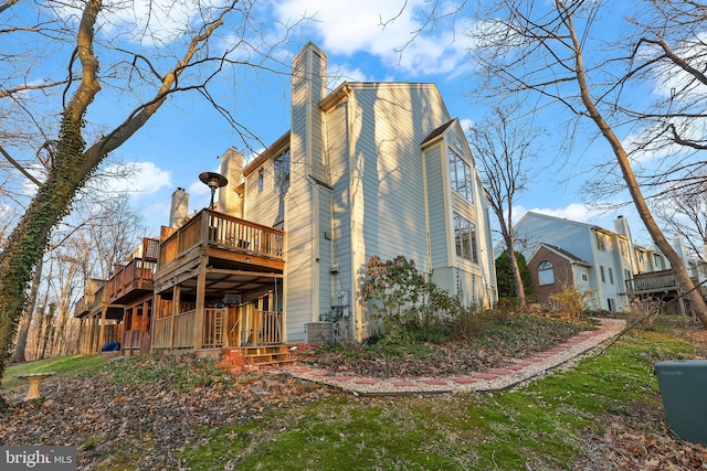 back of property with a wooden deck, central AC unit, and a chimney