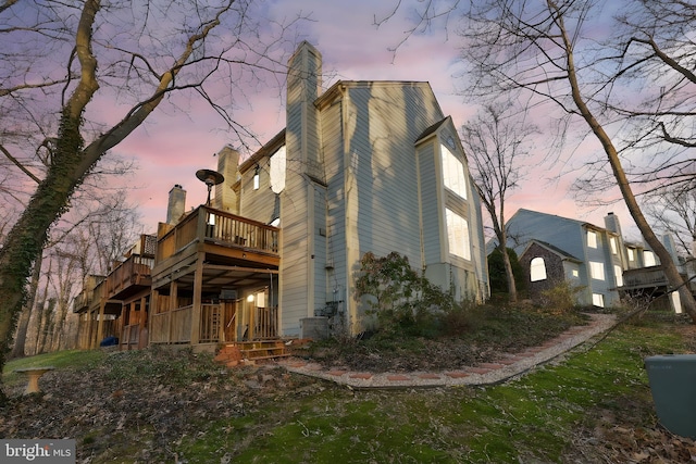 rear view of property with cooling unit, a chimney, and a deck