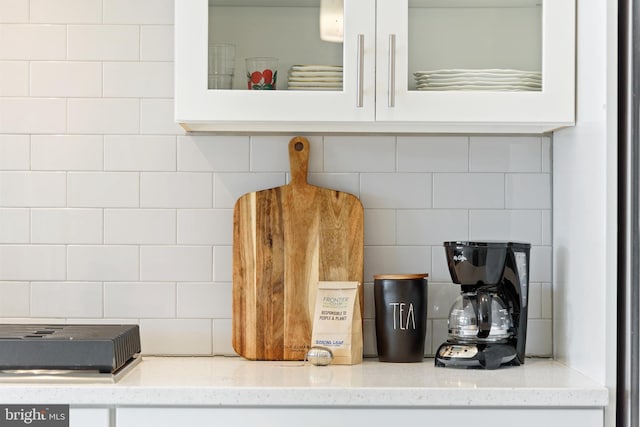 details with light stone counters, decorative backsplash, and white cabinetry