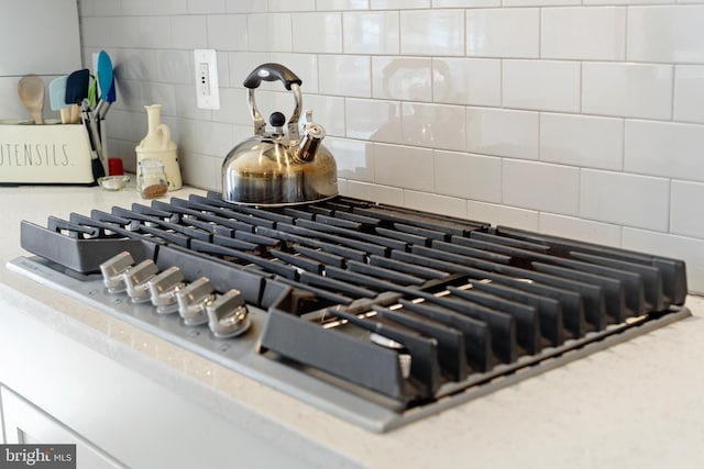 interior details featuring tasteful backsplash, light countertops, and stainless steel gas stovetop