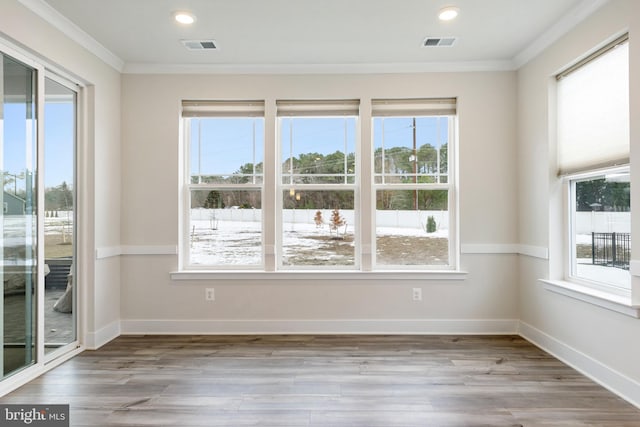 spare room featuring wood finished floors, visible vents, baseboards, recessed lighting, and crown molding