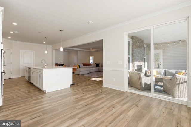 kitchen with ornamental molding, open floor plan, light wood-style floors, white cabinets, and dishwasher