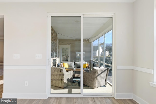 sitting room with a fireplace, rail lighting, wood finished floors, and baseboards