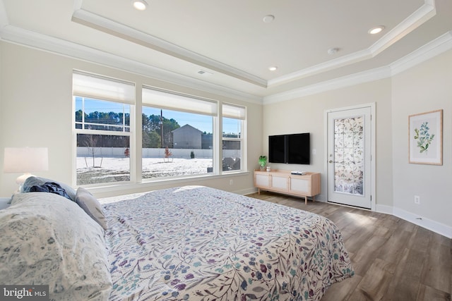 bedroom featuring a tray ceiling, baseboards, wood finished floors, and crown molding