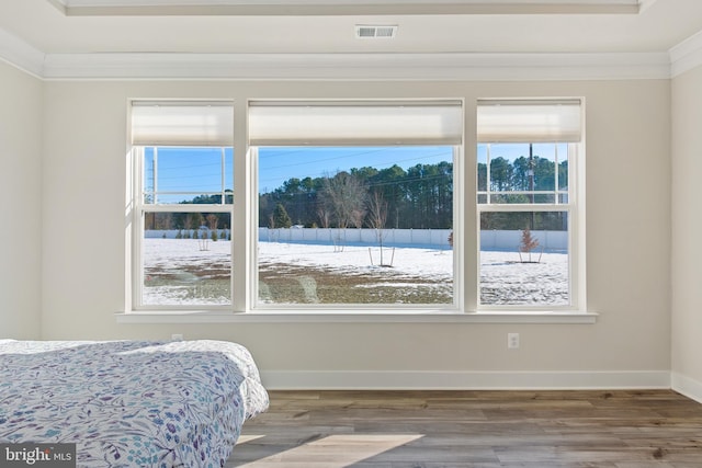 bedroom with crown molding, wood finished floors, visible vents, and baseboards