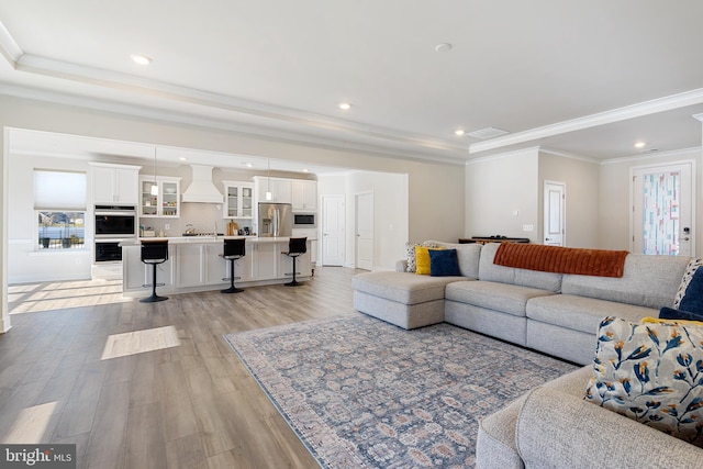 living room with light wood finished floors, visible vents, recessed lighting, and crown molding