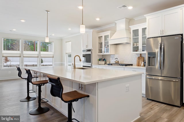 kitchen with a sink, custom range hood, appliances with stainless steel finishes, crown molding, and tasteful backsplash