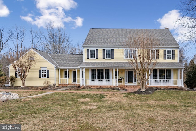 colonial-style house with a front yard, covered porch, and roof with shingles