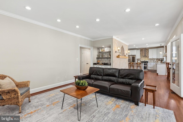 living room featuring baseboards, a dry bar, ornamental molding, recessed lighting, and wood finished floors