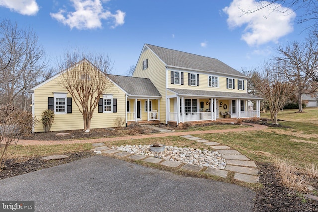 view of front of house with a front lawn, covered porch, and roof with shingles