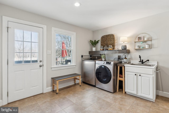 laundry room with baseboards, washer and clothes dryer, recessed lighting, cabinet space, and a sink