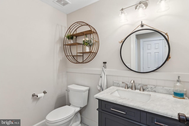 bathroom with vanity, toilet, visible vents, and wainscoting