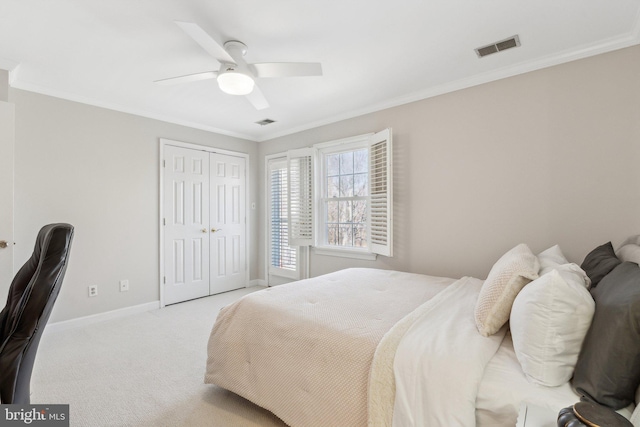 bedroom with baseboards, visible vents, carpet floors, a closet, and crown molding