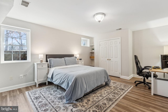 bedroom featuring visible vents, baseboards, and wood finished floors