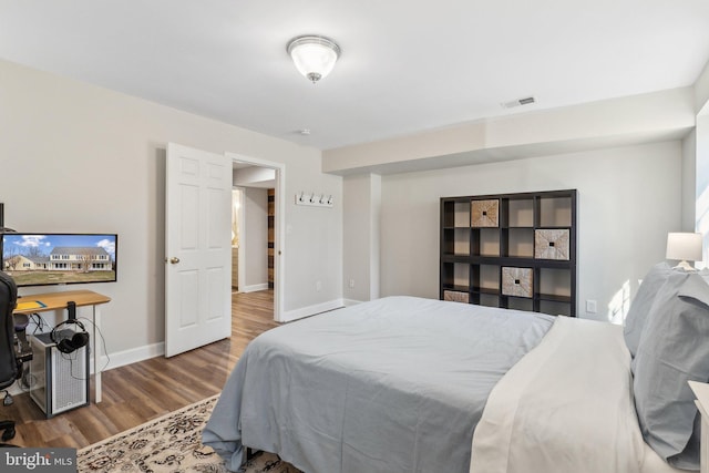 bedroom with visible vents, baseboards, and wood finished floors