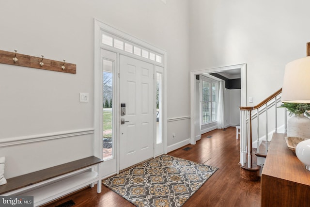 entrance foyer featuring a towering ceiling, baseboards, wood finished floors, and stairs