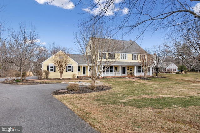 view of front of house with driveway, a porch, and a front yard