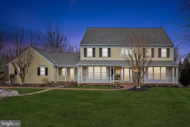 view of front of house with a porch, a front lawn, and a shingled roof