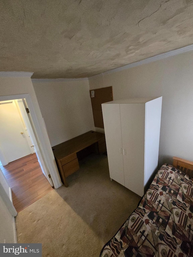 bedroom with wood finished floors, a textured ceiling, and ornamental molding