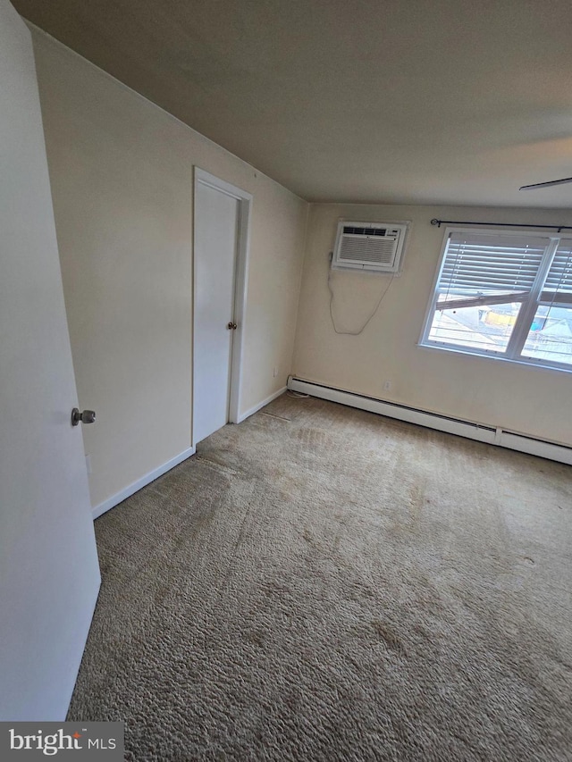 carpeted spare room with a wall mounted air conditioner, baseboards, and baseboard heating