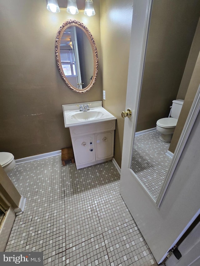 half bathroom featuring tile patterned flooring, toilet, vanity, and baseboards