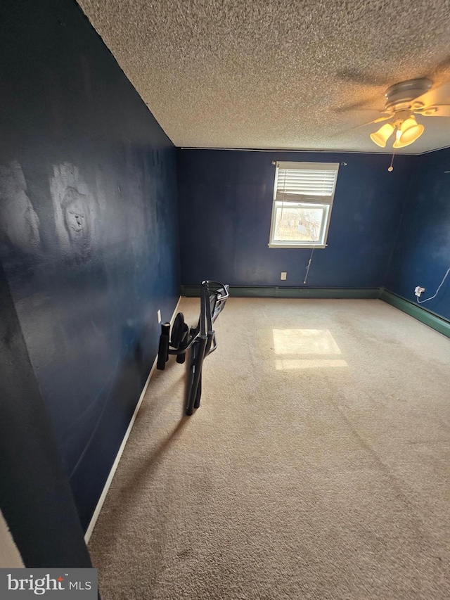 carpeted empty room featuring ceiling fan, baseboards, and a textured ceiling