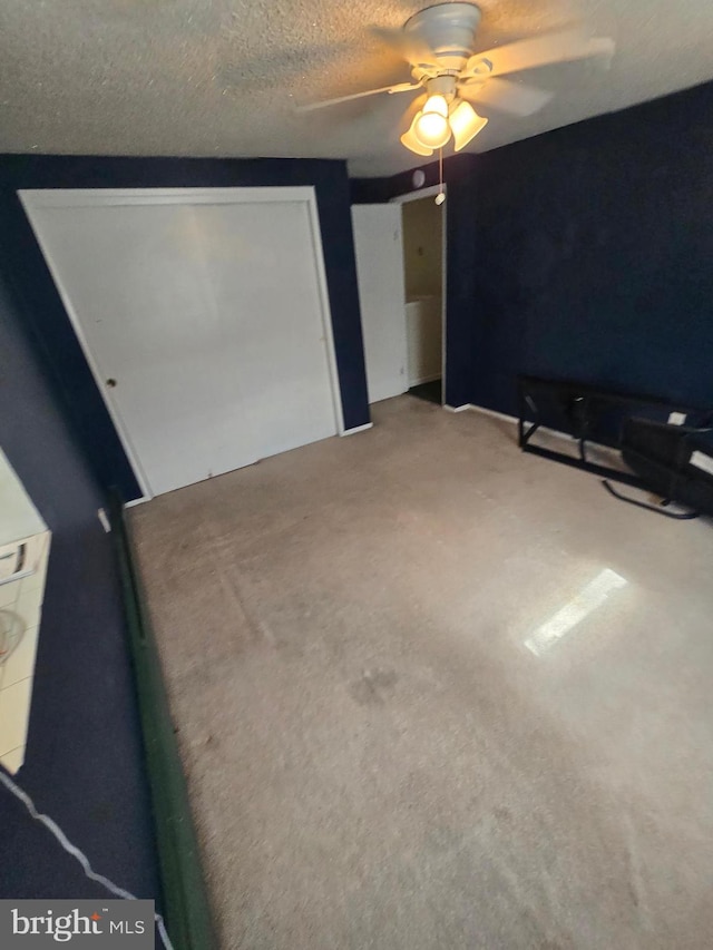 unfurnished bedroom featuring ceiling fan, carpet floors, and a textured ceiling