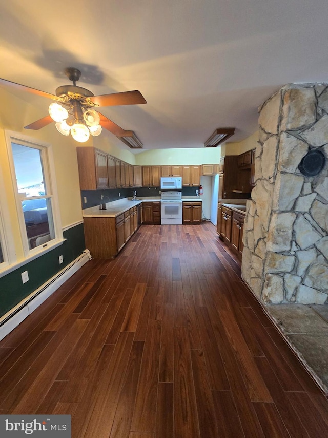 kitchen with brown cabinetry, white appliances, ceiling fan, and dark wood-style flooring