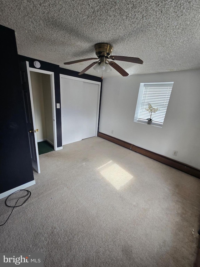 unfurnished bedroom featuring light carpet, baseboards, a textured ceiling, and ceiling fan